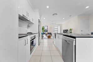 Uma cozinha moderna com armários brancos, eletrodomésticos de aço inoxidável e uma ilha central.