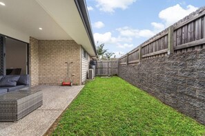 Un jardin avec un espace patio, un mur en briques et un mur en pierres.
