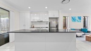 Een moderne keuken met witte kasten, een centraal eiland en een roestvrijstalen spoelbak.