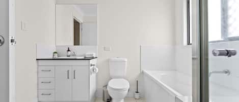 A modern bathroom with a toilet, sink, and shower area.