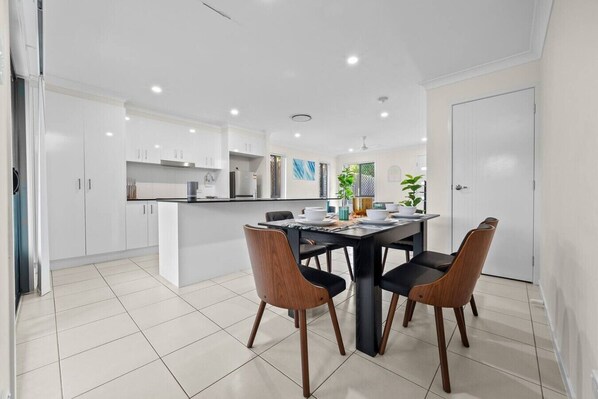 A modern kitchen with white cabinets, a dining table with chairs, and a white door.