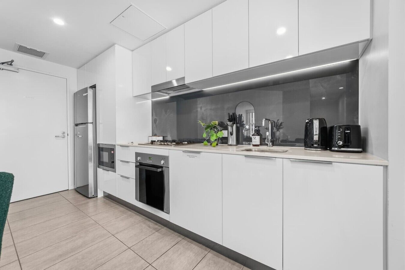 A modern kitchen with white cabinets, stainless steel appliances, and a large window.