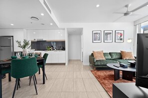 A modern living space with a dining area, sofa, and a TV. - Valley Stay Stylish Apartment |Parking |Pool & Gym (Newstead)