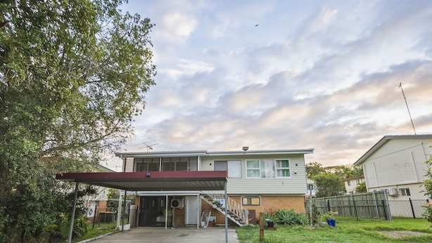 A two-story residential building with a covered driveway and a staircase leading to the entrance. - Great Value Renoted Studio| Near Griffith & Shops (Nathan)