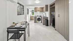 A modern kitchen with a washing machine, a refrigerator, and wooden cabinets. - Great Value Renoted Studio| Near Griffith & Shops (Nathan)