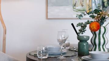 A dining table with a vase of flowers, a lamp, and a painting on the wall.