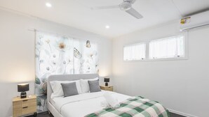 Una camera da letto moderna con un letto, due comodini, una ventola a soffitto e una finestra con tende.