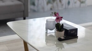 Un soggiorno moderno con un tavolino in vetro, una pianta in vaso e un computer portatile.