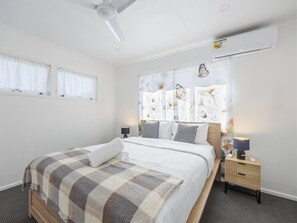 A hotel room with a bed, bedside tables, a ceiling fan, and a window with curtains. - Pet-Friendly & Great Value | Air-Con in Every BR (Sunnybank Hills)