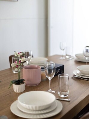 A dining table set with plates, glasses, and a pink vase with flowers. - Pet-Friendly & Great Value | Air-Con in Every BR (Sunnybank Hills)