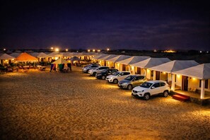 A row of tents with cars parked in front, set on a sandy ground. - Elite Family Desert Camp Jaisalmer (Jaisalmer)