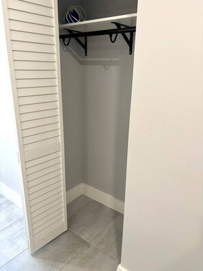 Ein Schrank mit weißer Tür, grauen Wänden und einer schwarzen Metallstange zum Aufhängen.