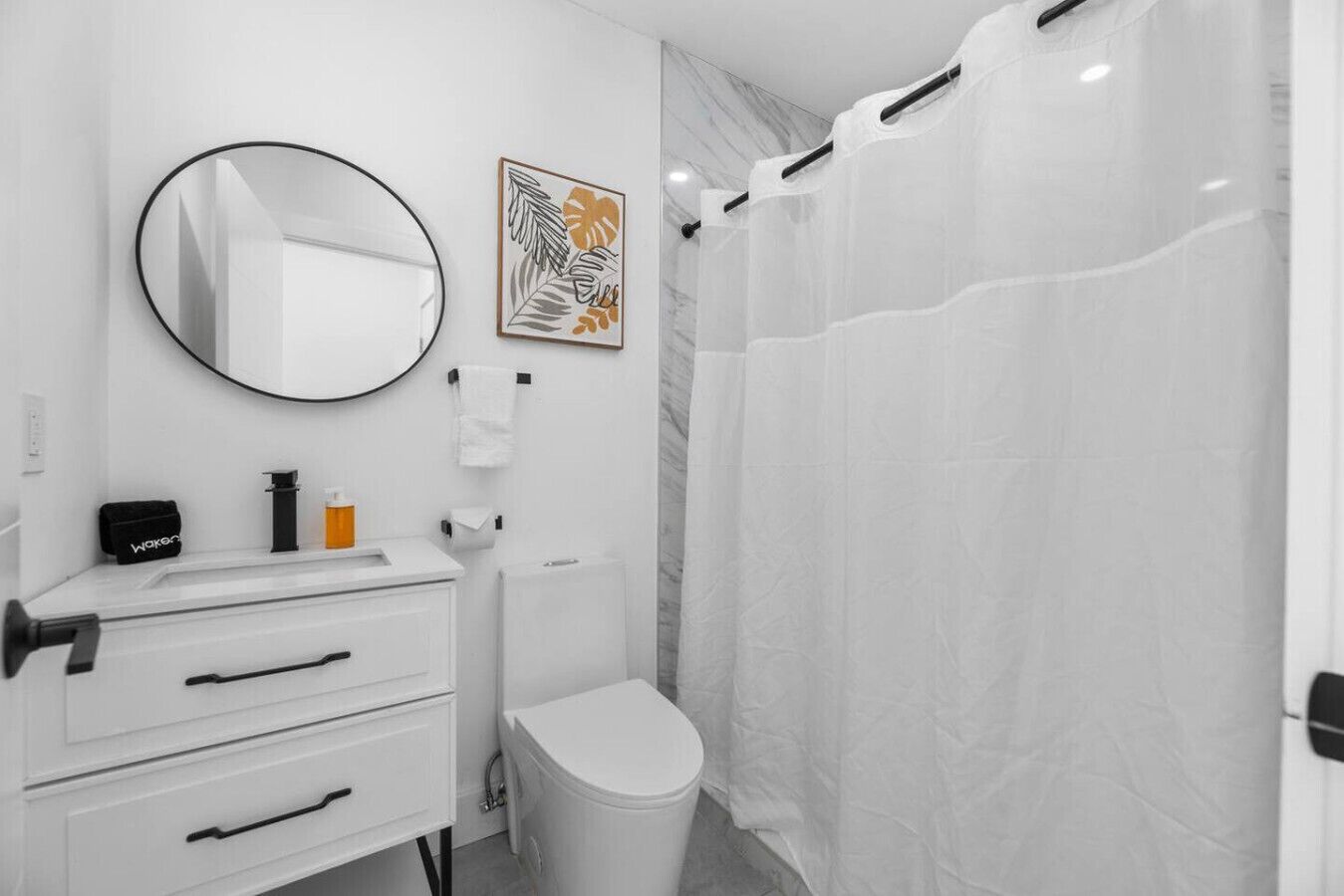 A bathroom with a white sink, a mirror, a toilet, and a shower curtain.