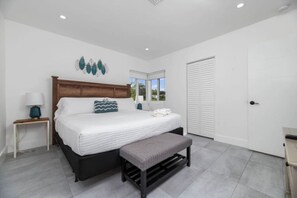 A bedroom with a bed, bedside tables, a bench, a wardrobe, and a window. - Your Downtown Getaway (Fort Lauderdale)
