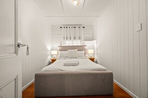 Ein Schlafzimmer mit einem Bett, Nachttischlampen, einem Beistelltisch und einer Tür mit einem Schlüsselbund.