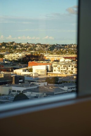 A cityscape with various buildings, including a prominent orange building with signage. - The Valley 1BR + Sofa Bed | Parking | Pool & Gym (Fortitude Valley)