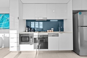 Eine moderne Küche mit weißen Schränken, Edelstahlgeräten und einer blauen Spritzschutzwand.