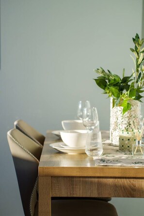 A dining table set with plates, glasses, and a vase with a plant. - The Valley 1BR + Sofa Bed | Parking | Pool & Gym (Fortitude Valley)
