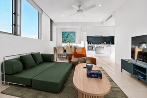 A modern living room with a sectional sofa, a coffee table, and a TV stand. - The Valley 1BR + Sofa Bed | Parking | Pool & Gym (Fortitude Valley)