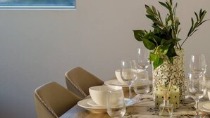 A dining table set with plates, glasses, and a decorative vase with greenery. - The Valley 1BR + Sofa Bed | Parking | Pool & Gym (Fortitude Valley)
