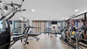 A modern gym with various cardio machines, weightlifting equipment, and dumbbells. - The Valley 1BR + Sofa Bed | Parking | Pool & Gym (Fortitude Valley)