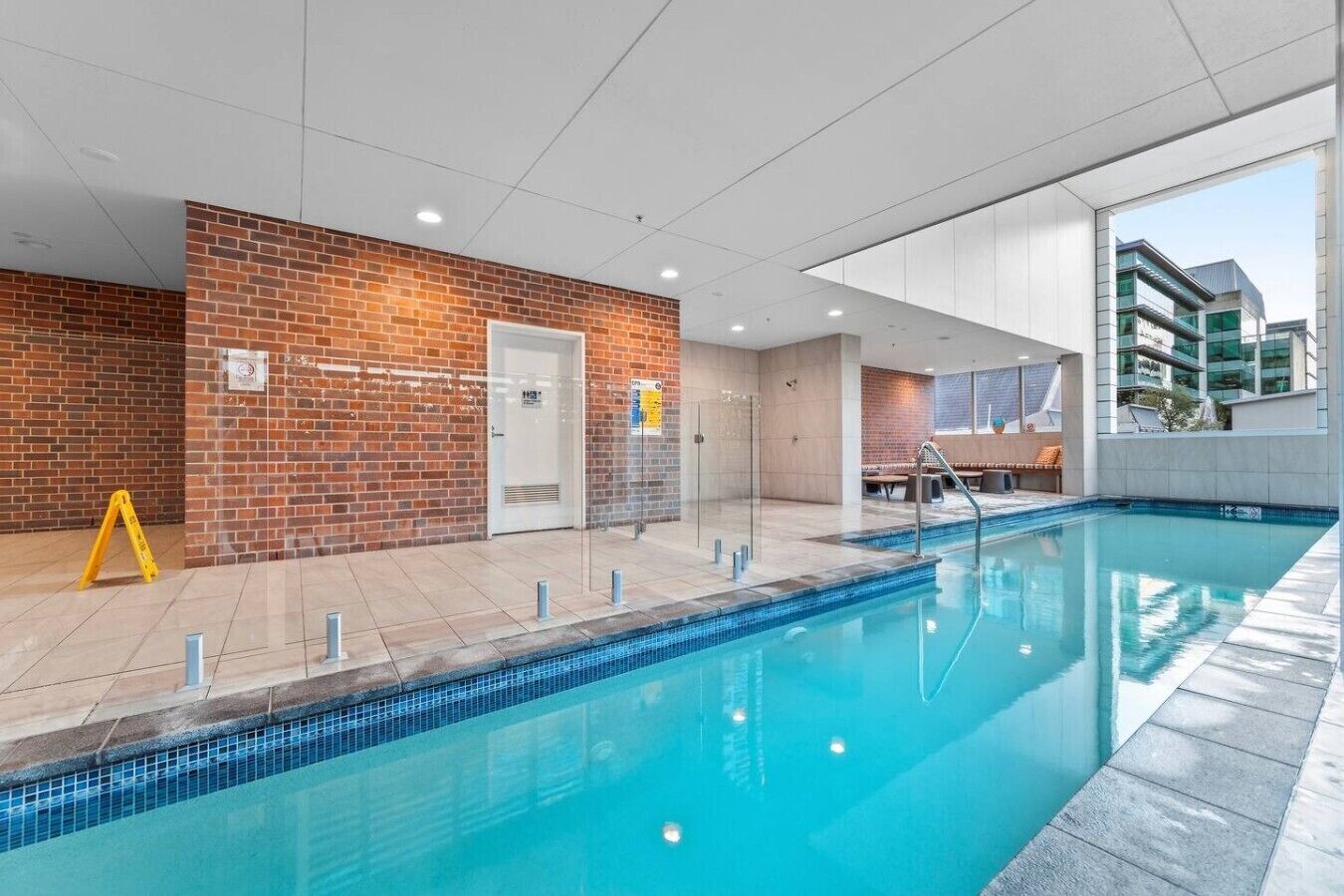 A modern indoor swimming pool with a clear view of the adjacent building.