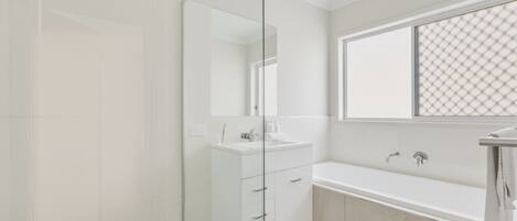 A modern bathroom with a glass shower enclosure, a white vanity with a mirror, and a bathtub.