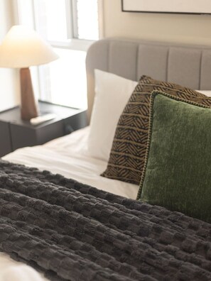 A bed with a dark blanket, a pillow with a geometric pattern, and a green pillow. - Stylish 4BR Family Retreat | Peaceful & Convenient (Park Ridge)