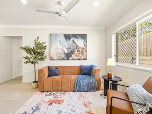 A living room with a sofa, a coffee table, a lamp, a painting, and a potted plant. - Stylish 4BR Family Retreat | Peaceful & Convenient (Park Ridge)