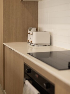 Eine Küche mit weißer Arbeitsplatte, einem Toaster und einem Holzkabinett.