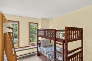 A bunk bed with a patterned bedspread, a window with a view of greenery, and a wooden ladder. - Harmony Pines | Hot Tub & Beach Access (Lake Harmony)