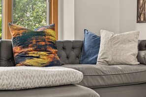 A sectional sofa with a patterned cushion, a tufted back, and a geometric-patterned pillow. - Harmony Pines | Hot Tub & Beach Access (Lake Harmony)