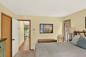 A bedroom with a bed, a desk, a chair, and a door leading to a balcony. - Harmony Pines | Hot Tub & Beach Access (Lake Harmony)