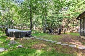 A backyard with a grill, a dining table with chairs, and a small cabin-like structure. - Harmony Pines | Hot Tub & Beach Access (Lake Harmony)