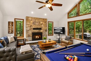 A living room with a stone fireplace, a pool table, a sofa, and a television. - Harmony Pines | Hot Tub & Beach Access (Lake Harmony)