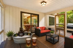 A covered outdoor seating area with a sofa, a table, and a grill. - Harmony Pines | Hot Tub & Beach Access (Lake Harmony)