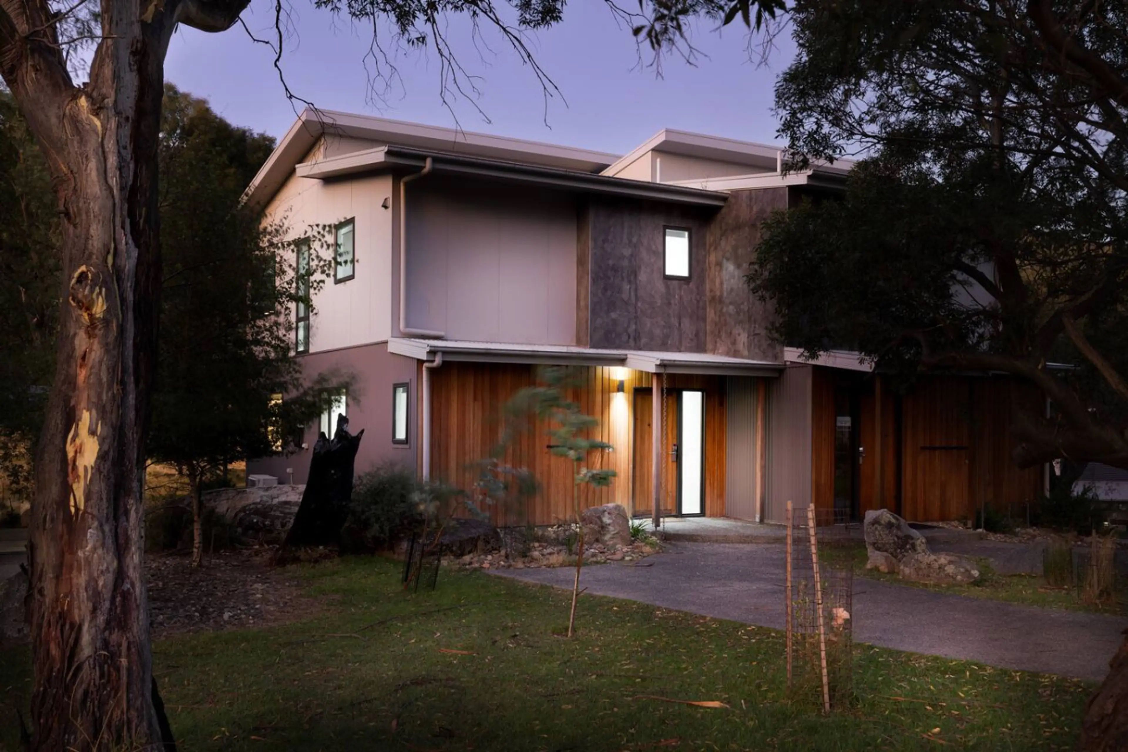 A modern two-story house with a flat roof, large windows, and a well-maintained lawn.