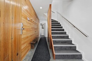 Un couloir en bois menant à un escalier muni d’une main courante.