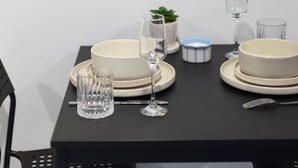 A dining table set with plates, glasses, and cutlery, a small potted plant, and a framed artwork above. - Great Value|Renovated Studio|Prime Location|Aircon (Nathan)