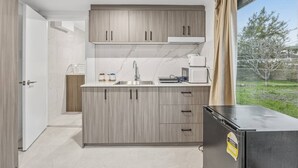 A modern kitchen with a built-in island, stainless steel appliances, and a view of the outdoors. - Great Value|Renovated Studio|Prime Location|Aircon (Nathan)