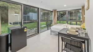 A modern room with a bed, a dining table set for two, and a refrigerator. - Great Value|Renovated Studio|Prime Location|Aircon (Nathan)