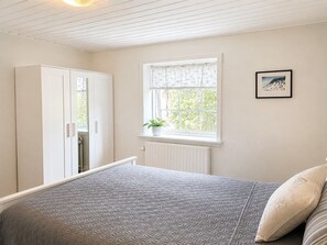 A bedroom with a bed, a wardrobe, a window with a view, and a framed picture on the wall. - "Edin" - 4km from the sea by Interhome (Løkken)