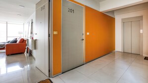 A modern hotel corridor with a sofa, a desk, and a door marked with the number 201.
