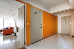 A modern hotel corridor with a sofa, a desk, and a door marked with the number 201.