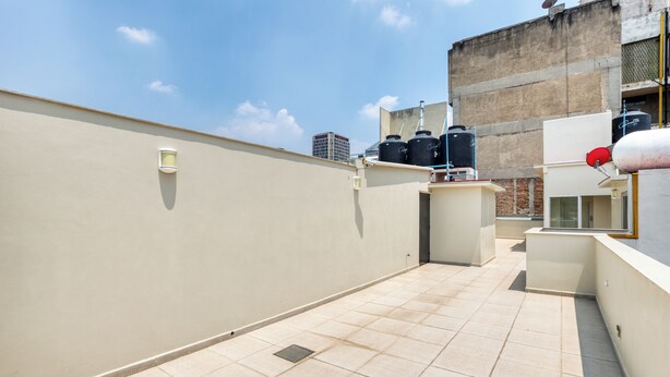 A rooftop terrace with a tiled floor, a water tank, and a satellite dish.