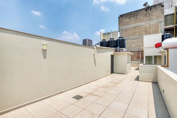 A rooftop terrace with a tiled floor, a water tank, and a satellite dish.