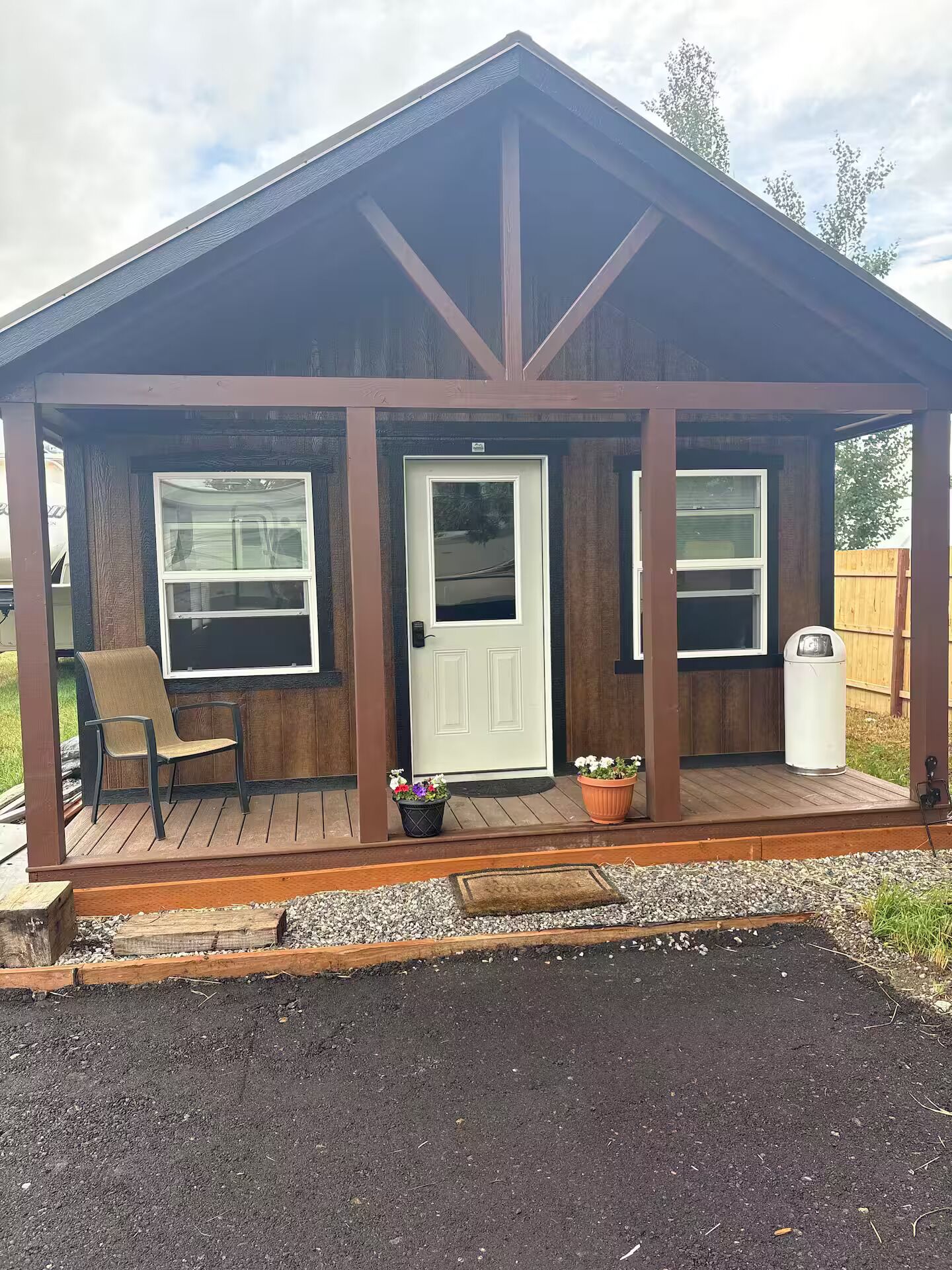 A wooden structure with a porch, a door, and two windows.