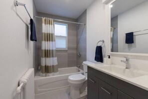 A modern bathroom with a bathtub, toilet, and vanity.