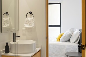 A modern bathroom with a round sink, towel rings, and a mirror.
