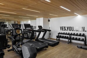 A gym with treadmills, ellipticals, and a wall with motivational text.